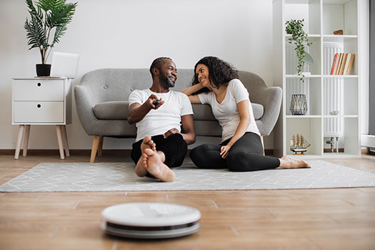 couple-using-remote-control-to-robotic-vacuum-clea